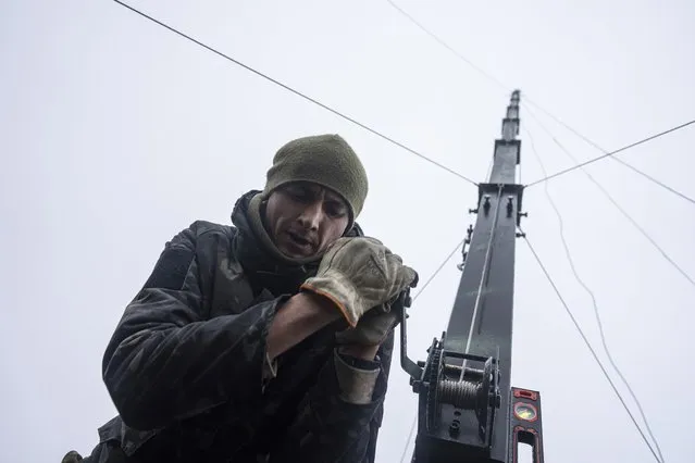 Ukrainian servicemen from 127 brigade prepare a telescopic tower with a remote camera installed on a Soviet car “Volga” that was recast to observe and correct fire on the front line near Kharkiv, Ukraine, Sunday, December 25, 2022. (Photo by Evgeniy Maloletka/AP Photo)