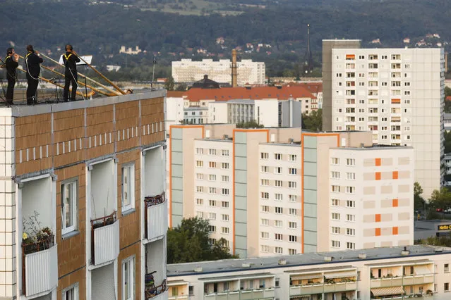 A musician with alp horns perform on the roof of an apartment block for a concert featuring distant harmonies, at a time when cultural events have been disrupted by the coronavirus pandemic, in the Prohlis neighborhood in Dresden, Germany, Saturday, September 12, 2020. About 33 musicians of the Dresden Sinfoniker perform a concert named the “Himmel ueber Prohils”, The Sky above Prohlis, on the roof-tops of communist-era apartment blocs in the Dresden neighborhood Prohlis. (Photo by Markus Schreiber/AP Photo)