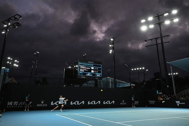 Spain's Pablo Carreno Busta hits a shot under dark clouds against France's Benjamin Bonzi during their men's singles match on day four of the Australian Open tennis tournament in Melbourne on January 19, 2023. (Photo by William West/AFP Photo)