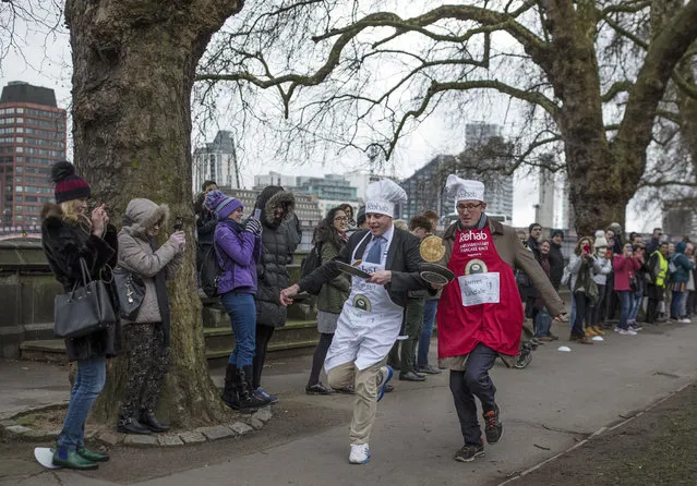 The BBC's Diplomatic correspondent James Landale (right) and MP Matt Warman (left) approach the first corner in the annual Parliamentary Pancake Race in Victoria Tower Gardens on Shrove Tuesday on February 13, 2018 in London, England. The annual Pancake Race, which raises money for the charity Rehab, sees teams of politicians and journalists racing around a circuit whilst tossing pancakes in frying pans. The team of journalists won this year's event. (Photo by Dan Kitwood/Getty Images)