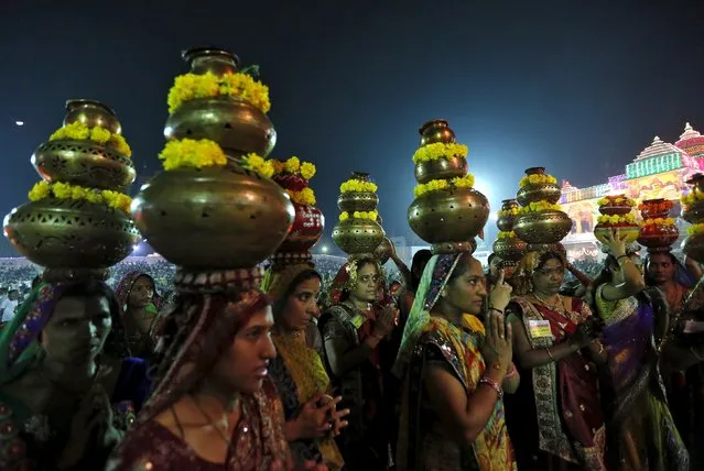 Hindu women carrying decorated metal pitchers pray after taking part in Garba, a traditional folk dance, during the celebrations to mark the Navratri festival at Surat in the western state of Gujarat, India, October 21, 2015. (Photo by Amit Dave/Reuters)