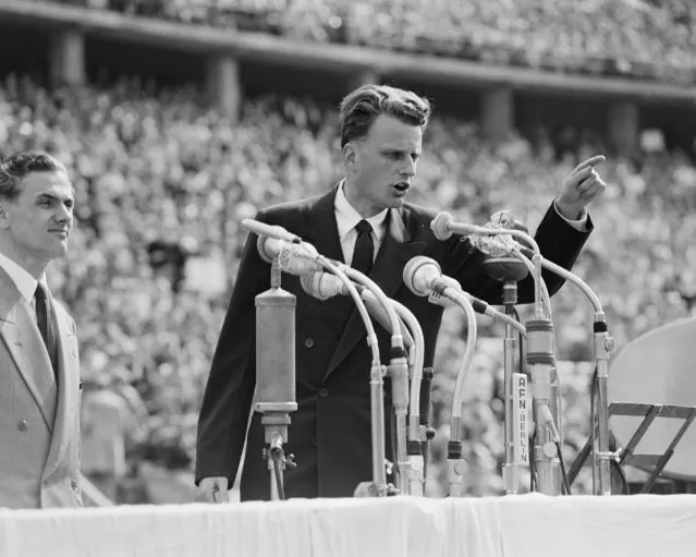 In this June 27, 1954 file photo, Evangelist Billy Graham speaks to over 100,000 Berliners at the Olympic Stadium in Berlin, Germany.   Graham, who transformed American religious life through his preaching and activism, becoming a counselor to presidents and the most widely heard Christian evangelist in history, has died. Spokesman Mark DeMoss says Graham, who long suffered from cancer, pneumonia and other ailments, died at his home in North Carolina on Wednesday, Feb. 21, 2018. He was 99. (Photo by AP Photo)