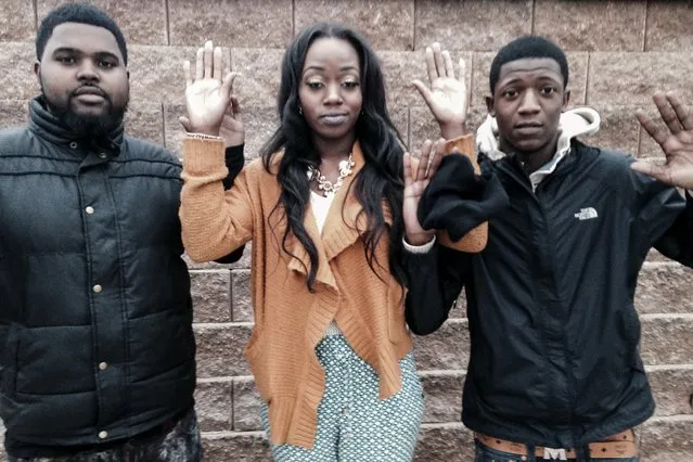 (L-R) Aaron Askew, 23, Johnnita Aldridge, 21, and Alexander Freeman, 24, pose for a photograph with their hands-up outside a restaurant in Ferguson, Missouri, November 30, 2014. The three say police arrested them along with another friend without cause at a gas station during the protests. (Photo by Emily Flitter/Reuters)