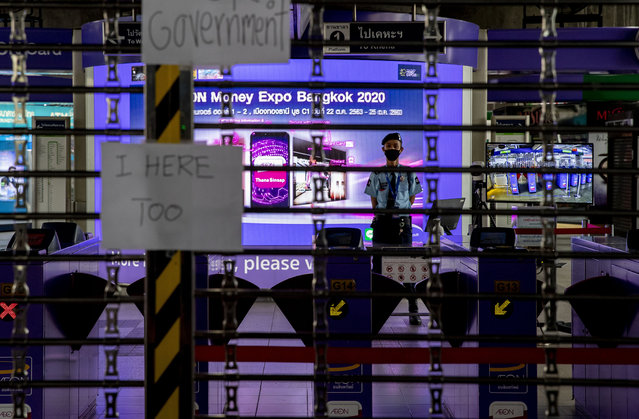 A security guard stands watch as placards against shutting down mass transport systems hang at Ashok BTS station in Bangkok, Thailand, Sunday, October 18, 2020. The authorities in Bangkok on Sunday shut down a mass transit line as Thailand's capital city braced for a fifth straight day of determined anti-government protests. (Photo by Gemunu Amarasinghe/AP Photo)