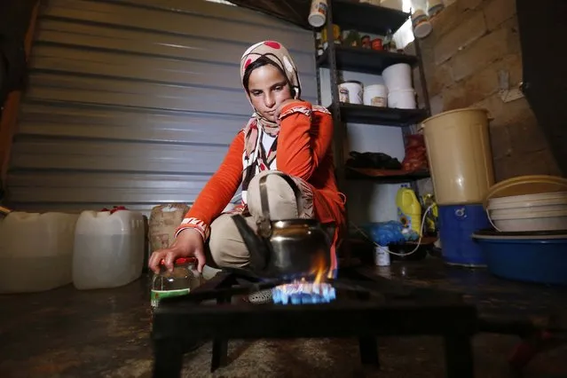 A Syrian refugee girl makes tea inside a caravan at the Al Zaatari refugee camp in the Jordanian city of Mafraq, near the border with Syria, December 7, 2014. A lack of funds has forced the United Nations to stop providing food vouchers for 1.7 million Syrian refugees in Jordan, Lebanon, Turkey, Iraq and Egypt, the World Food Programme (WFP) said on December 1. (Photo by Muhammad Hamed/Reuters)