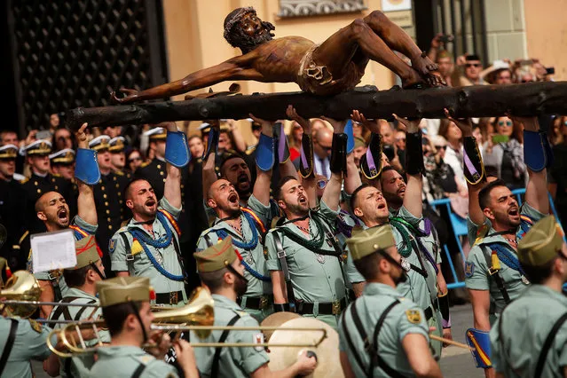 Spanish legionnaires carry a statue of the Christ of Mena outside a church during a ceremony ahead of the Mena brotherhood procession during Holy Week, in Malaga, Spain, March 29, 2018. (Photo by Jon Nazca/Reuters)