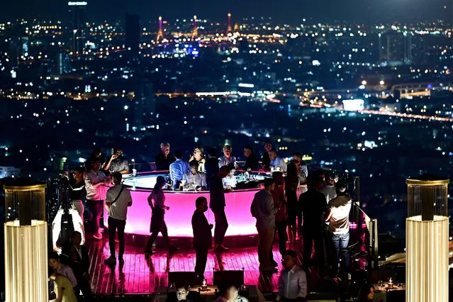 This photo taken on March 17, 2023 shows visitors enjoying a drink at the rooftop Lebua Sky Bar in Bangkok. Thailand's capital Bangkok, home to an estimated 11 million people, is one of the worlds most popular destinations, with millions of visitors arriving each year to enjoy the city's legendary nightlife and street food, ornate temples and luxury malls – the kingdom is now banking on a full recovery for the tourism sector following the Covid pandemic. (Photo by Manan Vatsyayana/AFP Photo)