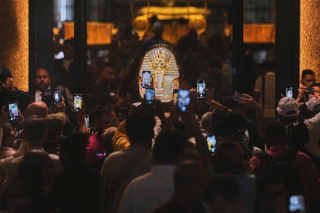 People hold mobile devices in front of the golden burial mask of King Tutankhamun during the first day for visitors after the official opening of the Grand Egyptian Museum in Giza, Egypt, Tuesday, November 4, 2025. (Photo by Amr Nabil/AP Photo)