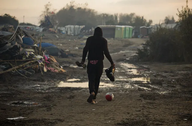 A migrant kicks a ball as he past tents destroyed in the makeshift migrant camp known as “the jungle” near Calais, northern France, Friday, October 28, 2016. Thousands of migrants dispersed this week from the now-torched camp they had called home in Calais are struggling to adapt to unfamiliar surroundings in towns and villages throughout France. (Photo by Emilio Morenatti/AP Photo)