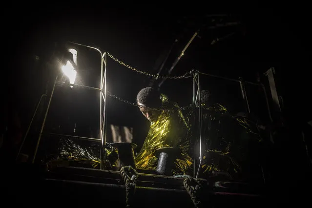 A man wrapped in a thermal blanket rests on board the Louise Michel rescue vessel after being rescued from an overcrowded rubber boat sailing adrift, 70 miles southwest Malta, in the Central Mediterranean sea, Saturday, August 29, 2020. A rescue ship painted and sponsored by British artist Banksy saved another 130 migrants stranded on a rubber boat in the Southern Mediterranean Sea. (Photo by Santi Palacios/AP Photo)