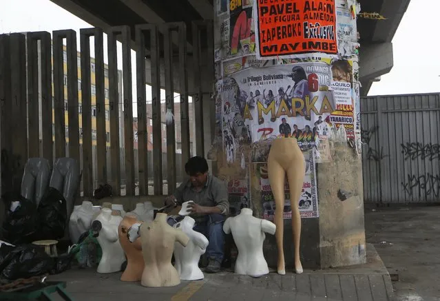 A man sells mannequins under the railway track of the Metro train in downtown Lima, Peru December 1, 2015. (Photo by Mariana Bazo/Reuters)