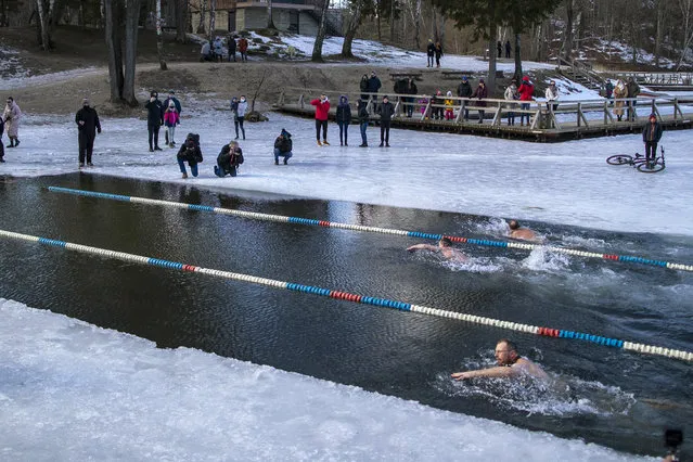 Swimmers compete during a winter swimming competition in the 25 meters long ice hole on a lake near Vilnius, Lithuania, Saturday, March 6, 2021. The water temperature was 3 degrees Celsius (37.4 degrees Fahrenheit), while the air was –3 degrees Celsius (26,6 degrees Fahrenheit). (Photo by Mindaugas Kulbis/AP Photo)