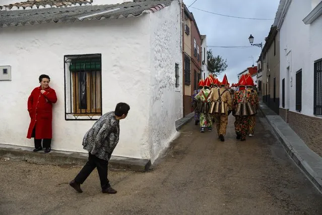 A woman looks as members of the Endiablada brotherhood march during the 'Endiablada' traditional festival in Almonacid Del Marquesado, Spain, Tuesday, Feb. 3, 2015. The "Endiablada" (The Brotherhood of the Devils) festivals are celebrated each Feb. 2-3 in the central Spanish town of Almonacid del Marquesado since medieval times or before. In the festival, men from the town dress up as devil-type characters in colorful jumpsuit costumes and red miter hats. (AP Photo/Daniel Ochoa de Olza)