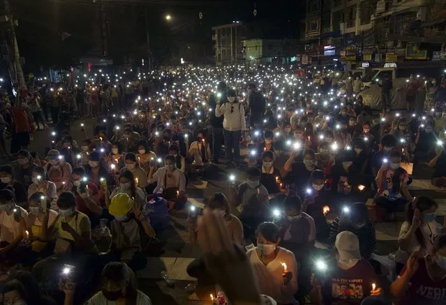 Anti-coup protesters turn on the LED light of their mobile phones during a candlelight night rally in Yangon, Myanmar Sunday, March 14, 2021. At least four people were shot dead during protests in Myanmar on Sunday, as security forces continued their violent crackdown against dissent following last month's military coup. (Photo by AP Photo/Stringer)
