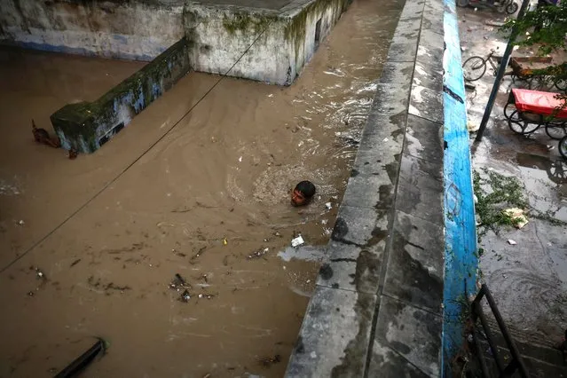 A man swims through an alley flooded with the rising waters of river Yamuna after heavy monsoon rains in New Delhi, India on July 12, 2023. (Photo by Adnan Abidi/Reuters)