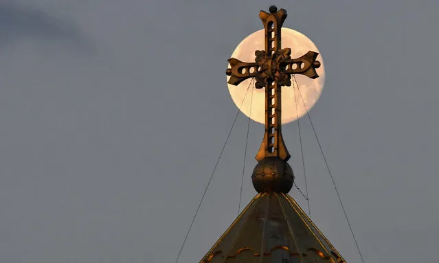 The full moon is seen behind a cross on top of the Holy Trinity Cathedral in Tbilisi, Georgia on March 30, 2021. (Photo by Vano Shlamov/AFP Photo)