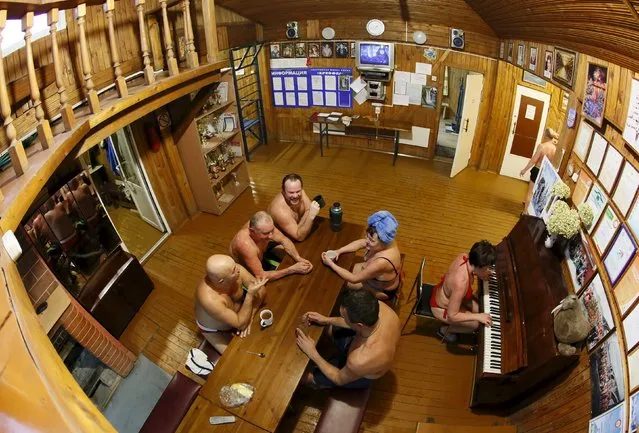 Members of the Cryophile winter swimmers club gather inside the wooden clubhouse on the banks of the Yenisei River in the Siberian city of Krasnoyarsk, Russia, December 13, 2015. A winter swimming club in the Siberian city of Krasnoyarsk gathers young and old from all walks of life. They share a love of bracing, cold water, in air temperatures that can reach minus 30 degrees Celsius or lower. The Cryophile club - named after organisms that thrive in the cold - has about 300 members. (Photo by Ilya Naymushin/Reuters)