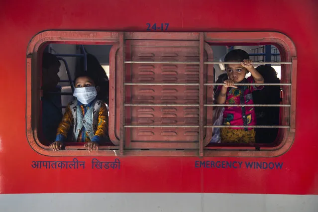 A boy wearing a face mask looks through the window of a train at a railway station in Gauhati, India, Monday, April 19, 2021. India now has reported more than 15 million coronavirus infections, a total second only to the United States. (Photo by Anupam Nath/AP Photo)