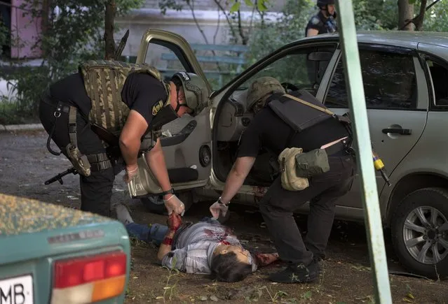 Police officers inspect a dead body of a man killed by the Russian shelling in city center in Slavyansk, Donetsk region, Ukraine on Monday, June 27, 2022. (Photo by Efrem Lukatsky/AP Photo)