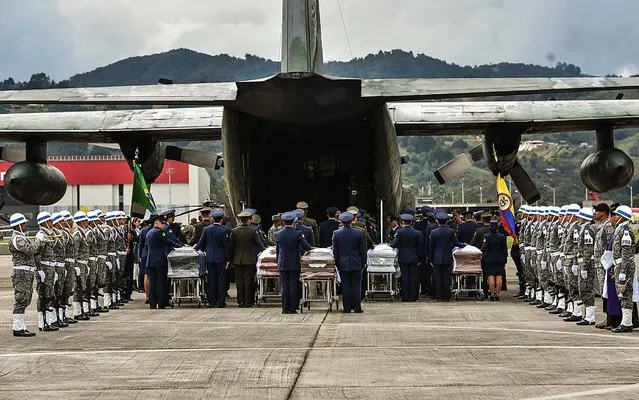 Members of the Colombian Air Force prepare to load onto a plane in Rionegro, Antioquia department, Colombia, on December 2, 2016 the coffins with the remains of the members of the Brazilian football team Chapecoense Real who died in a plane crash in the Colombian mountains earlier this week. The bodies of the 71 victims killed in the crash that wiped out the Brazilian team began arriving home Friday, as mourners prepared a massive funeral. The other victims – 64 Brazilians, five Bolivians and a Venezuelan – are being flown home on a series of flights throughout the day. (Photo by Luis Acosta/AFP Photo)