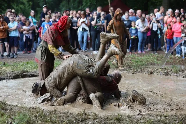 Men sit in a mud hole at the 2022 Dirty Pig Festival in Hergisdorf, Germany on June 6, 2022 at the festival site on the Wildbahn. At the forest party there, the actual Dirty Pig Festival, winter is symbolically driven out. For this, the men jump into a mud hole. (Photo by Matthias Bein/dpa/Alamy Live News)