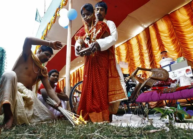 A Hindu priest burns jute sticks as part of a ritual as a couple take their wedding vows at a mass marriage ceremony at Bahirkhand village, north of Kolkata February 8, 2015. (Photo by Rupak De Chowdhuri/Reuters)