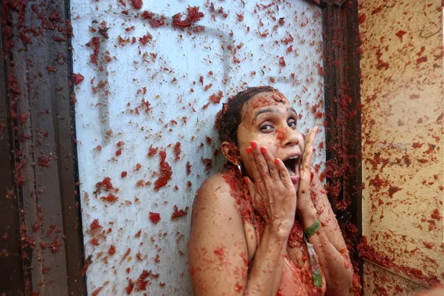 A woman reacts during the annual tomato fight fiesta called “Tomatina”, tomato fight fiesta, in the village of Bunol near Valencia, Spain, Wednesday, August 30, 2023. Thousands gather in this eastern Spanish town for the annual street tomato battle that leaves the streets and participants drenched in red pulp from 120,000 kilos of tomatoes. (Photo by Alberto Saiz/AP Photo)