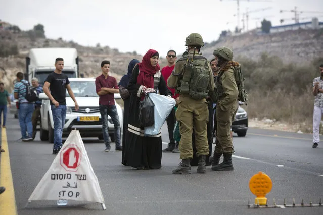 Palestinians wait at an Israeli checkpoint near the scene of a shooting attack at Barkan industrial zone in the West Bank Sunday, October 7, 2018. A Palestinian attacker opened fire at joint Israeli-Palestinian industrial zone in the West Bank Sunday, killing two Israelis and seriously wounding a third, the military said. (Photo by Majdi Mohammed/AP Photo)