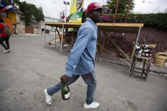 A protester holds a ready to throw empty bottle, during a street protest after it was announced that the runoff Jan. 24, presidential election had been postponed, in Port-au-Prince, Haiti, Friday, January 22, 2016. (Photo by Dieu Nalio Chery/AP Photo)