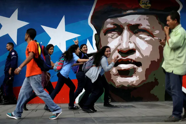 Venezuelan citizens walks past a mural depicting former Venezuela's late President Hugo Chavez in Caracas, Venezuela, December 1, 2016. (Photo by Ueslei Marcelino/Reuters)