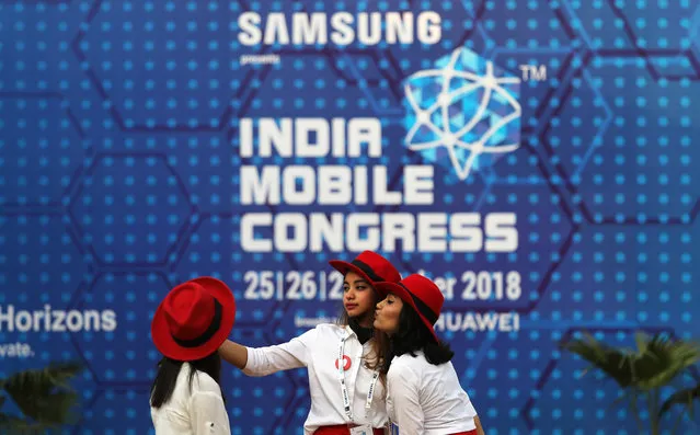 Girls take selfies in front of a board at the India Mobile Congress 2018 in New Delhi, October 26, 2018. (Photo by Anushree Fadnavis/Reuters)