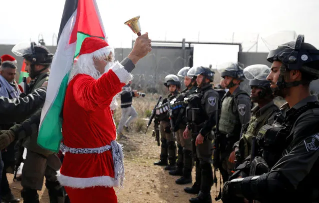 A Palestinian protester, dressed as Santa Claus, stands in front of Israeli border police officers during a protest against the Israeli barrier, in the West Bank village of Bilin near Ramallah December 23, 2016. (Photo by Mohamad Torokman/Reuters)
