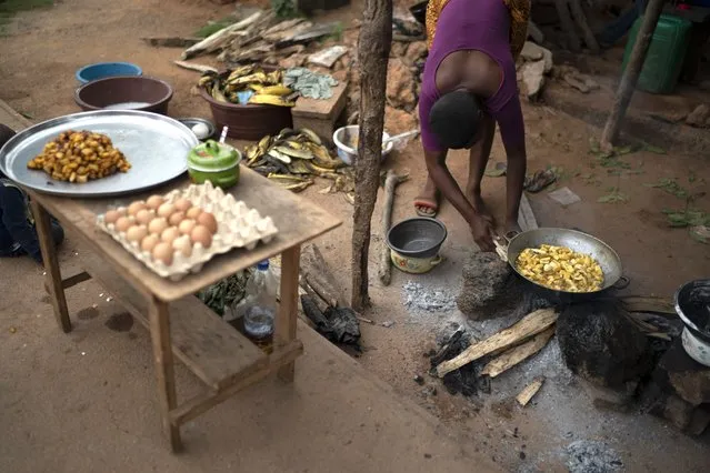 A woman prepares traditional food known as alloco, fried bananas, to sell on the street during a celebration for the return of the former Ivorian president Laurent Gbagbo in Mama, Ivory Coast, Saturday, June 19, 2021. The town's residents and people from other villages say that they will keep celebrating every day until Gbagbo arrives in his hometown. After nearly a decade, the ex-president returned to his country after his acquittal on war crimes charges that was upheld at the International Criminal Court earlier this year. (Photo by Leo Correa/AP Photo)