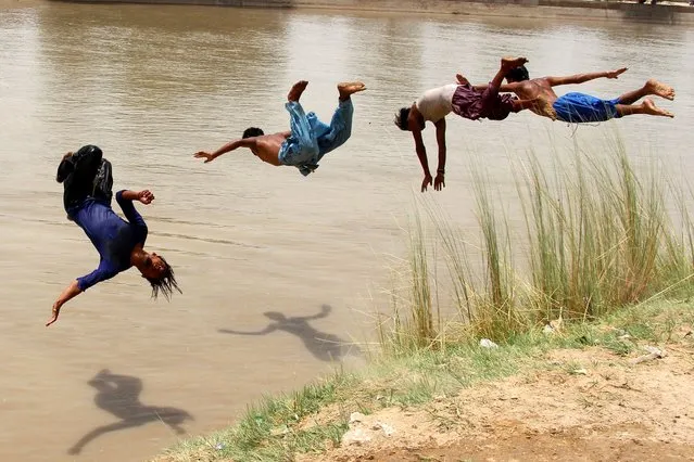 Pakistani boys jump in the water to cool off in a pond to beat the heat wave continues in Larkana, Pakistan, 26 June 2021. Pakistan's Meteorological Department (PMD) said the weather in the city will remain hot and humid for the next three days. (Photo by Waqar Hussain/EPA/EFE)