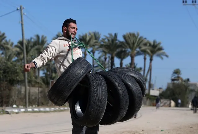 Palestinian Mohamed Barka, locally known as a “super hero” for his strength, lifts tyres tied to a rope with his teeth during his performance in Deir Al-Balah,in central Gaza, on January 4, 2016. (Photo by Mohammed Abed/AFP Photo)