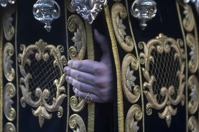 The hand of a penitent from Los Estudiantes brotherhood gets a grip onto a platform that several penitents carry with a statue of the Virgin Mary during a Palm Sunday Holy week procession in Madrid, Spain, Sunday, March 29, 2015. (Photo by Paul White/AP Photo)
