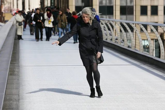 A woman struggles to keep her balance as she crosses the Millennium Bridge during strong winds in London, March 31, 2015. (Photo by Stefan Wermuth/Reuters)