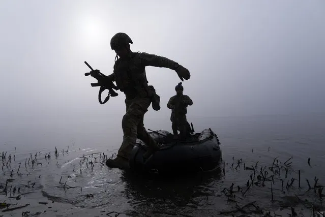 A Ukrainian serviceman jumps out of the boat on the shore of Dnipro river at the frontline near Kherson, Ukraine, Sunday October 15, 2023. (Photo by Mstyslav Chernov/AP Photo)