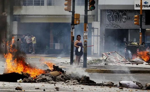 A woman in Buenos Aires bangs a pot during a street blockade, December 30, 2013, to protest against power outages affecting the city for two weeks. With temperatures passing 100 °F (37,8 °C), water and power outages blanket large swaths of Argentina's capital city, sparking protests and placing residents, particularly those in high-rise buildings, at risk. (Photo by Enrique Marcarian/Reuters)
