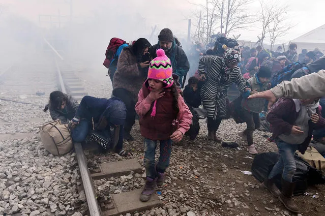 A child coughs as migrants and refugees run away after Macedonian police fired tear gas at hundreds of Iraqi and Syrian migrants who tried to break through the Greek border fence in Idomeni, on February 29, 2016. Greek police said more than 6,000 people were massed at the border, in a buildup triggered by Austria and Balkan states capping the numbers of migrants entering their territory. (Photo by Louisa Gouliamaki/AFP Photo)