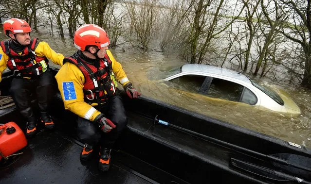 Members of the Avon and Somerset Police Underwater Search Unit inspect a submerged abandoned car as they head to the village of Muchelney in Somerset to offer support to local residents who have been isolated due to the high flood waters in the Somerset Levels since early January. Picture date: Sunday January 26, 2014. (Photo by Andrew Matthews/PA Wire)