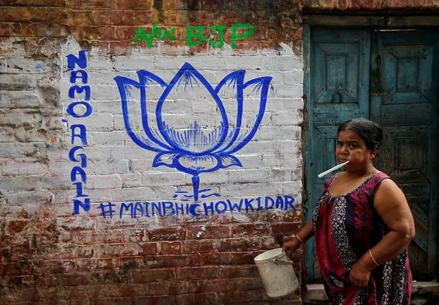A woman walks past a wall painted with the election symbol of India's ruling Bharatiya Janata Party (BJP) in an alley at a residential area in Kolkata, India, March 22, 2019. (Photo by Rupak De Chowdhuri/Reuters)
