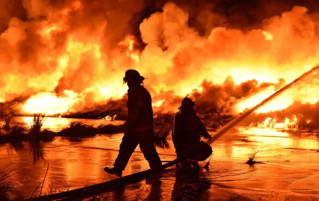 Firefighters work on a fire burning at the former Market Street Wharf early Sunday, October 17, 2021, in New Orleans. The remains of an abandoned river wharf went up in flames over the weekend in New Orleans as fireworks went off nearby, but officials haven’t yet determined whether the display played a role in the enormous fire. (Photo by Chief C. Mickal/New Orleans Fire Department Photo Unit via AP Photo)