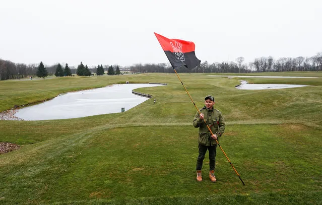 A protester holds an alternative Ukrainian flag on a golf field at the residence of Ukrainian President Viktor Yanukovych in Mezhyhirya village near of Kiev, Ukraine, February 22, 2014. Protesters took full control of the Yanukovych residence and provided free access of the premises for Ukrainian and the media. (Photo by Sergey Dolzhenko/EPA)