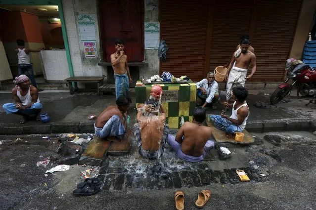 Men bathe at a roadside municipal tap in Kolkata, India, March 12, 2016. Some people in Kolkata earn a living by selling second-hand clothes, driving rickshaws or in the city’s food markets. Those too poor to afford a home of their own sleep where they work, helping people who moved to the city to find work to send money back home. Outside working hours residents of the city formerly called Calcutta might enjoy a game of chess or carrom, while children play soccer with friends. (Photo by Rupak De Chowdhuri/Reuters)