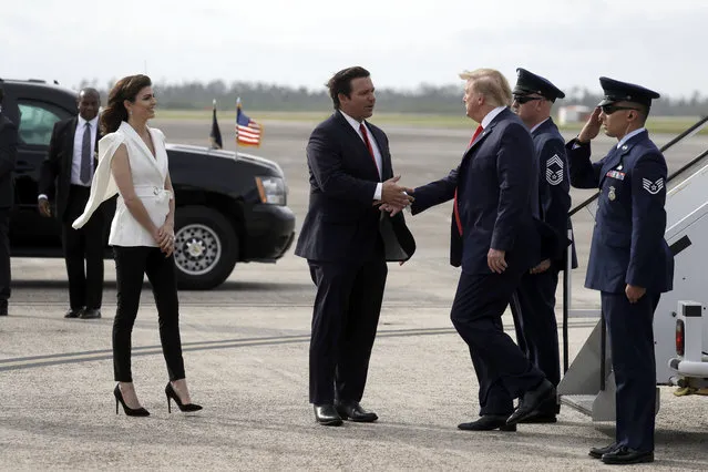 President Donald Trump shakes hands with Florida Gov. Ron DeSantis as he arrives at Tyndall Air Force Base to view damage from Hurricane Michael, and attend a political rally, Wednesday, May 8, 2019, at Tyndall Air Force Base, Fla. His wife, Casey DeSantis watches at left. (Photo by Evan Vucci/AP Photo)