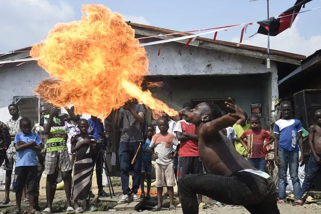 A dancer spits fire during a slum party at Oworonshoki district of Lagos, on November 27, 2021. In Oworonshoki, a poor district of Lagos, Nigeria's economic capital, an emerging artistic dance activists, Ennovate Dance House, is changing the narratives of the slum cummunity. The community which in the past was always in the bad news for cultism, violence and killings, suddenly is attracting tourist attention with a “Slum Party”, a yearly artistic dance festival being used by the group to give life and hope to the inhabitants. (Photo by Pius Utomi Ekpei/AFP Photo)