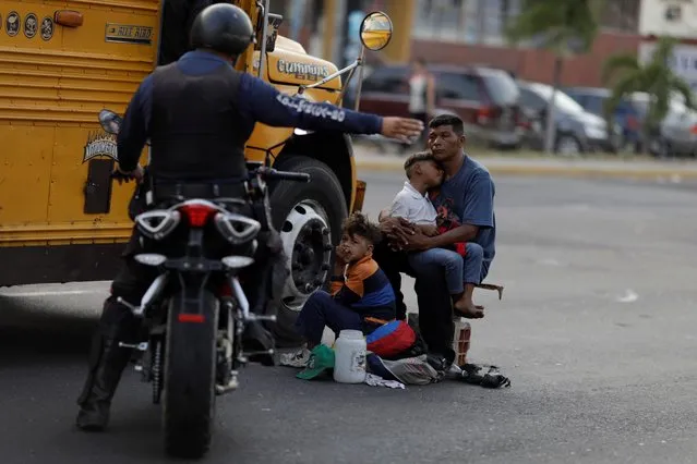 A Venezuelan police officer orders a man and his sons to move from the street where he was asking for donations, during a blackout in Maracaibo, Venezuela on April 11, 2019. (Photo by Ueslei Marcelino/Reuters)