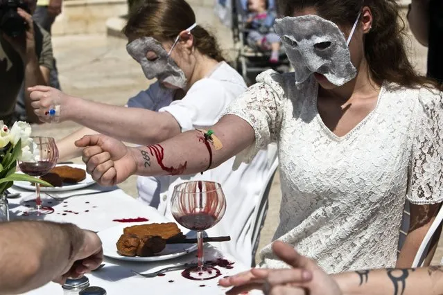 Activists from an animal rights movement take part in a protest piece whereby they draw their own blood to emphasize their ideology, in Tel Aviv, on March 23, 2014. (Photo by Nir Elias/Reuters)