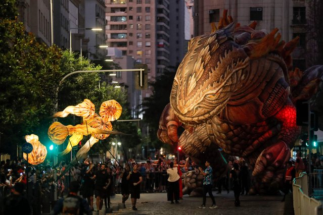 The inflatable dinosaur known as “Saurian” is seen during “Saurian and the Witnesses of Outer Space” -the night parade of the French Plasticiens Volants company- during the inauguration of the “Teatro a Mil” international festival, in front of La Moneda Presidential Palace in Santiago on January 3, 2023. (Photo by Javier Torres/AFP Photo)